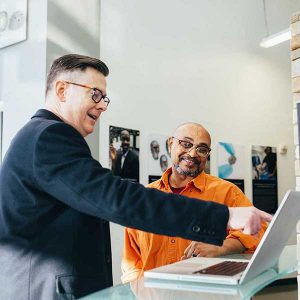 Businessmen collaborate on a laptop, discussing RTO compliance strategies.